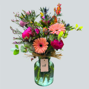 Arreglo floral en florero con peonías fucsias, gerberas durazno, eryngium azul y eucalyptus. Creación de Exóticas Flores®.