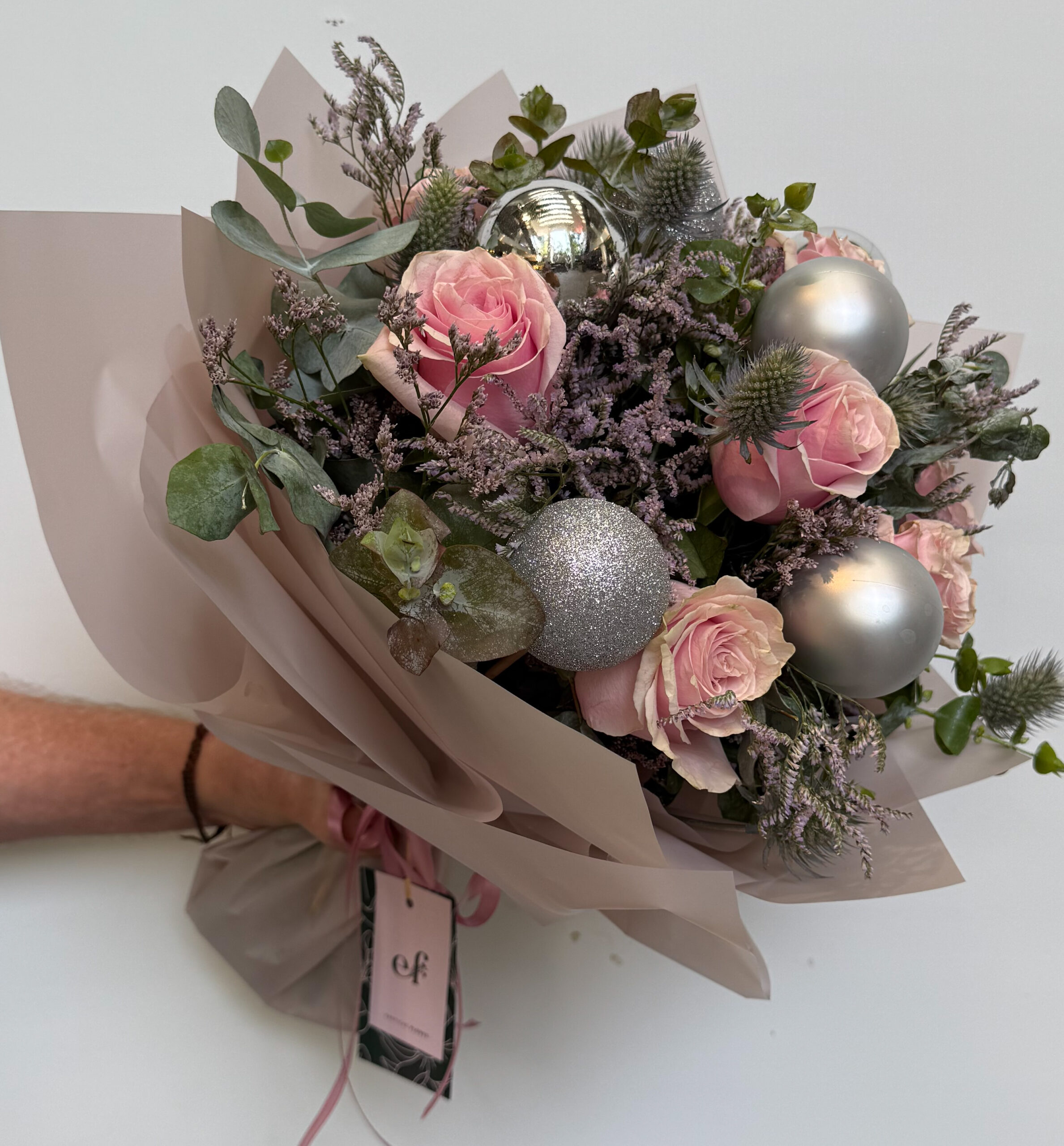 Ramo navideño elegante con rosas rosa pastel, eryngium, limonium y esferas plateadas, diseñado por Exóticas Flores.