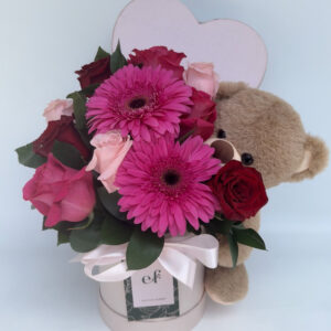 Arreglo floral romántico con rosas rosadas, gerberas fucsias y oso de peluche en box Exóticas Flores